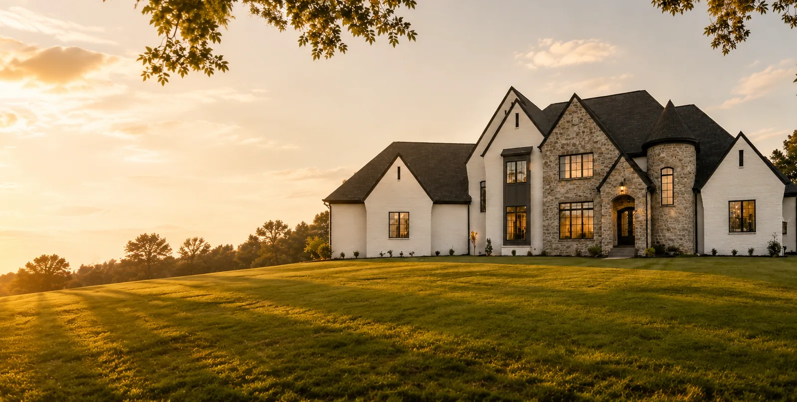 A home built by Curtis Austin at dusk, windows lit, seen across the lawn