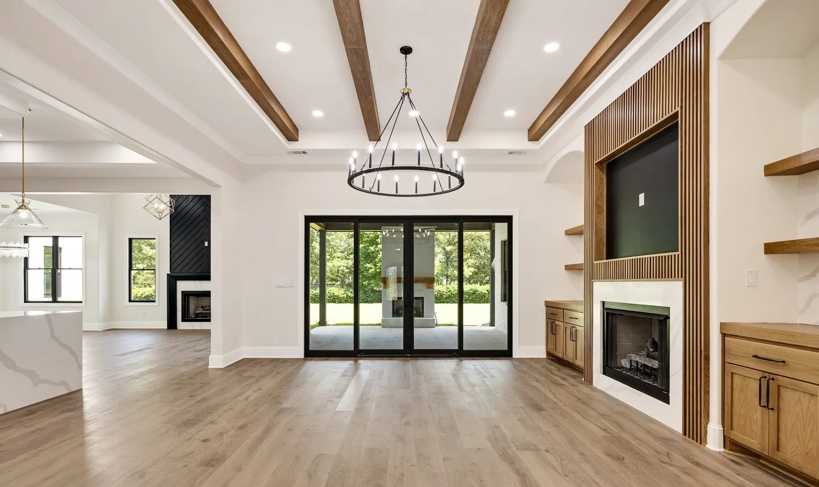 A finished living room with exposed beams and glass doors onto the lawn